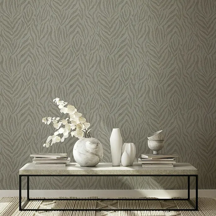 Marburg GZSZ Vliestapete Moderner Zebralook - Beige, Tieroptik, 10,05 x 0,53 m - Eine Nahaufnahme von Tapeten mit Zebramuster in Grau und Beige, dekoriert mit Vasen und Büchern auf einem Tisch.
