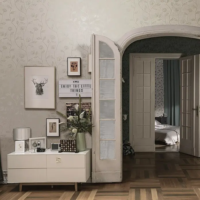 Marburg GZSZ Vliestapete Blumenranke - Weiß, Floral, 10,05 x 0,53 m - Kommode im Flur mit Deko und Blick durch eine Tür in ein Schlafzimmer. Die Kommode bietet Stauraum und ist ein dekoratives Element.