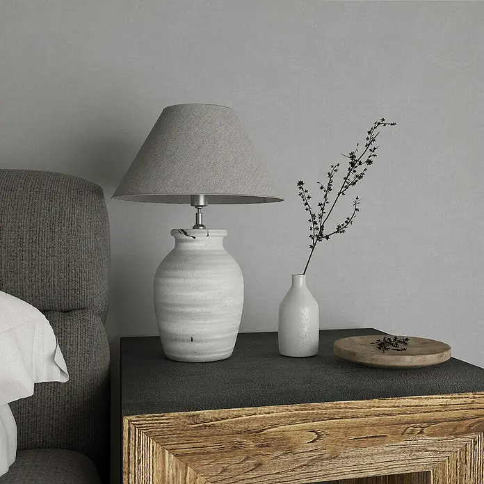 Marburg GZSZ Vliestapete - Mittleres Grau, Uni, 10,05 x 0,53 m - Nahaufnahme einer Nachttischlampe mit grauen Schirm, Vase und Holzschale auf einem rustikalen Nachttisch.