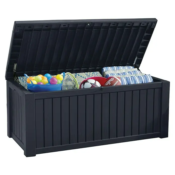 Keter Gartenbox Rockwood - 570 l, Kunststoff - Eine offene, dunkelblaue Gartenbox ist mit bunten Spielbällen, einer Badmintonschlägerausrüstung, einem Fußball, einem Football und gestreiften Kissen gefüllt.