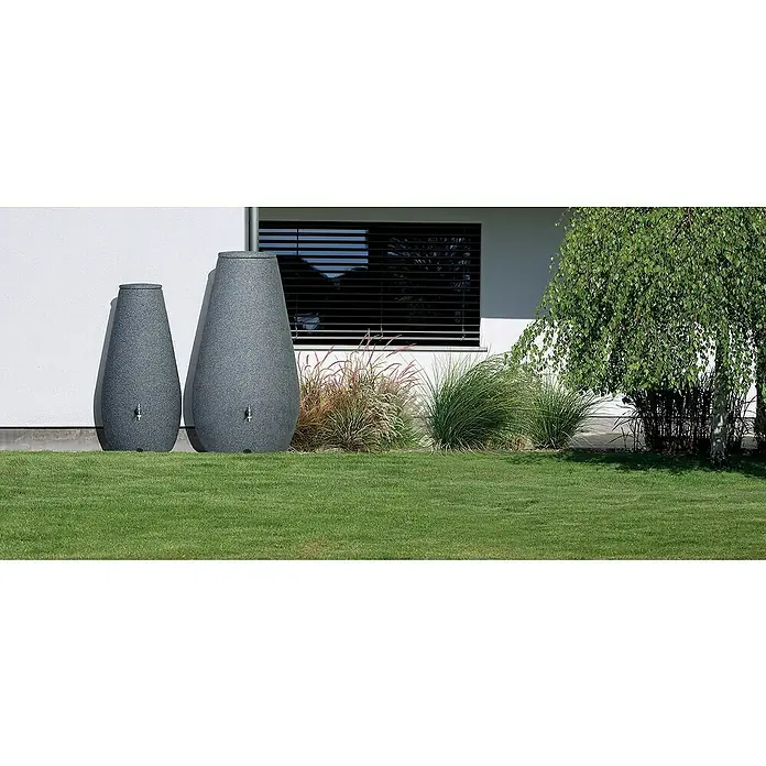 Arves Regenspeicher Drop - 200 l, Anthrazit, 1 Stk. - Graue Regentonne in Tropfenform im Garten vor einem weißen Haus mit Fenster und Bäumen. Praktische Wasserspeicher für den Garten.