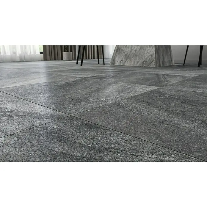 Terrassenfliese Cera 2.0 - 80 x 80 x 2 cm, Quarz Nero, Matt - Blick auf graue Bodenfliesen mit dunklen Fugen. Die Fliesen haben eine raue, strukturierte Oberfläche und sind in einem Schachbrettmuster verlegt.