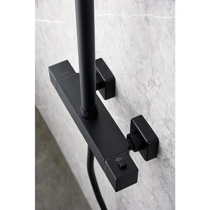 Imex Art Sistema de ducha - Grifo termostático, Negro - Primer plano detallado de un grifo de ducha negro con formas angulosas y una estética moderna sobre una pared de mármol.