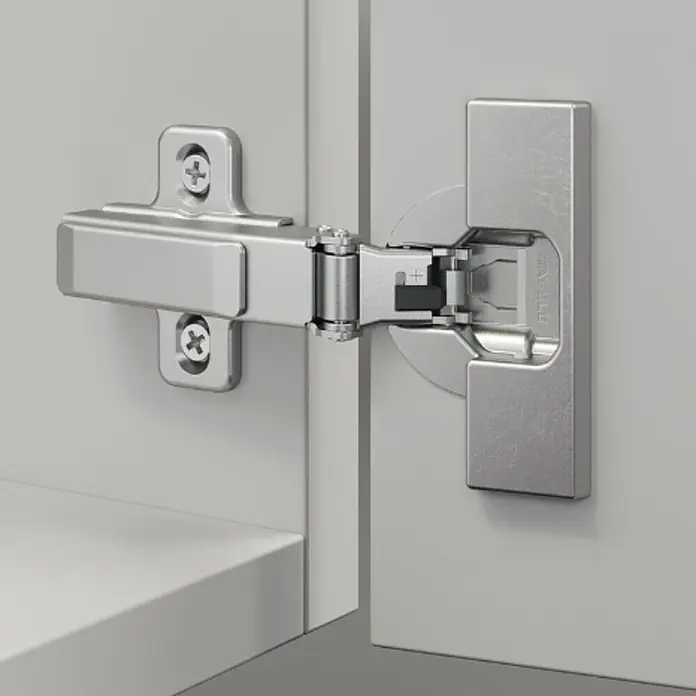 Stabilit Topfscharnier - Mittelanschlag, Durchmesser Topf: 35 mm, 110 ° - Detailaufnahme eines Schrankscharniers aus Metall, das an einer grauen Schranktür befestigt ist.