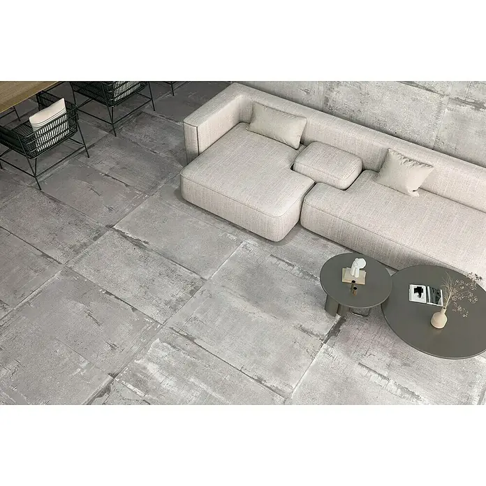 Feinsteinzeugfliese Bond Ash - 60 x 120 cm, Grau, Matt - Blick von oben auf ein stilvolles Wohnzimmer mit Betonbodenfliesen, grauen Sofas und Couchtischen.