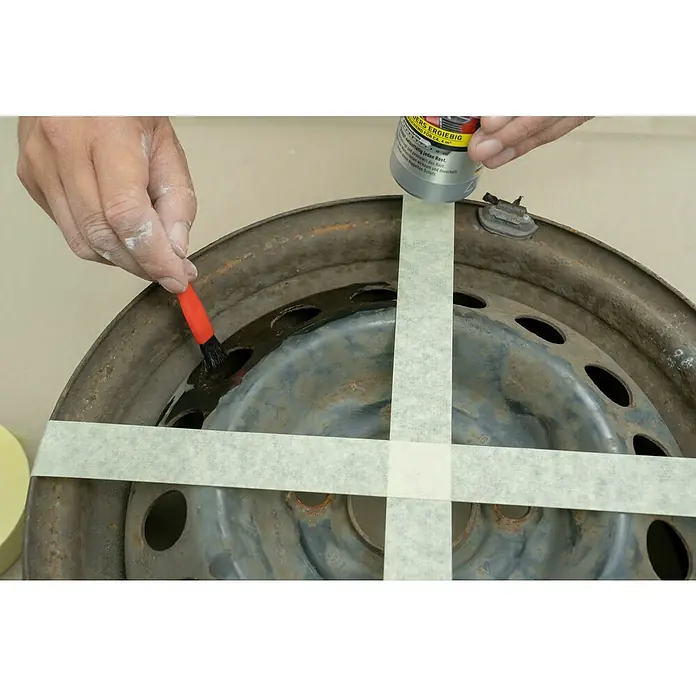 Nigrin Rost-Blocker - 200 ml - Ein Rostumwandler wird mit einem Pinsel auf eine rostige Felge aufgetragen, die mit Klebeband versehen ist.