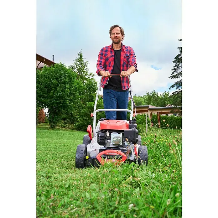 AL-KO Benzin-Rasenmäher Classic 5.14 SP-A - Hubraum: 139 cm³, Schnittbreite: 51 cm - Ein Mann mäht den Rasen mit einem roten Rasenmäher im Garten. Der Rasenmäher ist das Hauptprodukt im Bild.
