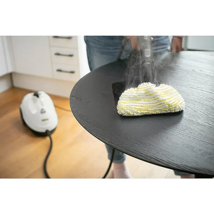 Kärcher Dampfreiniger SC 2 EasyFix - 1.500 W, Aufheizzeit: 6,5 min, Behältervolumen: 1 l - Ein Dampfreiniger säubert einen dunklen Holztisch mit einem gelb-weiß gestreiften Aufsatz. Das Gerät im Hintergrund ist ebenfalls von Kärcher.