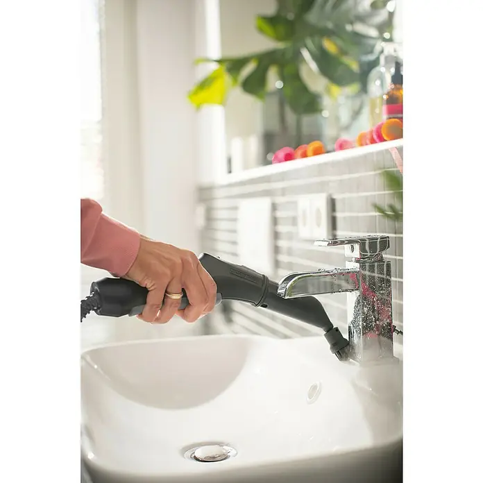 Kärcher Dampfreiniger SC 3 EasyFix1.900 W, Aufheizzeit: 0,5 min, Behältervolumen: 1 l - Eine Person reinigt mit einem Kärcher-Dampfreiniger einen verchromten Wasserhahn über einem Waschbecken, um Kalkablagerungen und Schmutz zu entfernen.