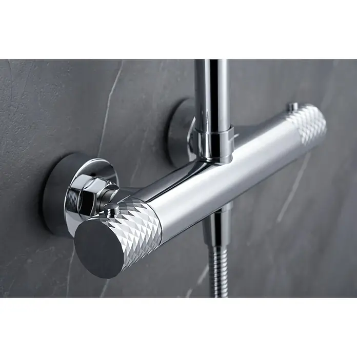 Imex Génova Sistema de ducha - Grifo termostático, Cromo - Primer plano de un termostato de ducha moderno y brillante con perillas moleteadas, sobre una pared gris tipo mármol.