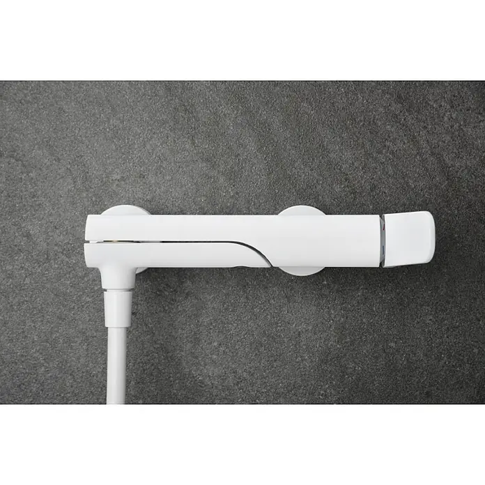 Imex Dinamarca Grifo monomando de bañera - Profundidad del grifo: 20,2 cm, Blanco, Mate - Primer plano de un grifo de ducha blanco montado en una pared gris. El diseño es moderno y minimalista.