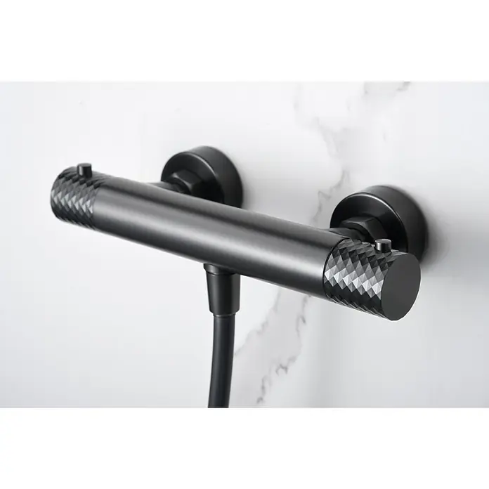 Imex Génova Grifo con termostato - Ancho: 29,5 cm, Black gun - Primer plano de un elegante grifo de ducha negro con un preciso patrón de diamante sobre un fondo de mármol.