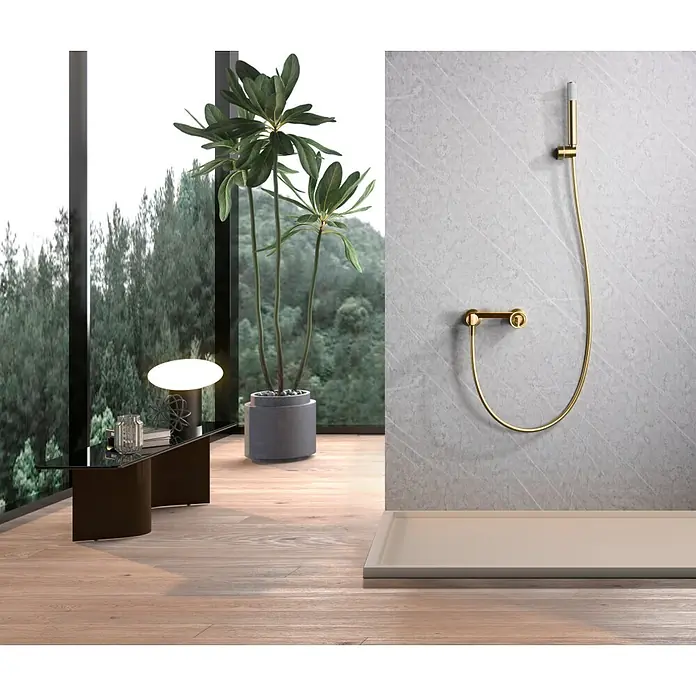 Imex Olimpo Grifo de ducha - Oro - La imagen muestra un elegante conjunto de ducha dorado sobre una pared de mármol gris, creando un ambiente de baño lujoso.