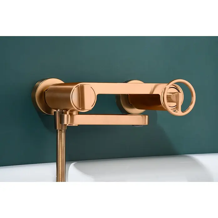 Imex Olimpo Grifo monomando de bañera - Oro rosa - Primer plano de un grifo dorado de pared con un diseño de rueda único, que combina elegancia y funcionalidad.