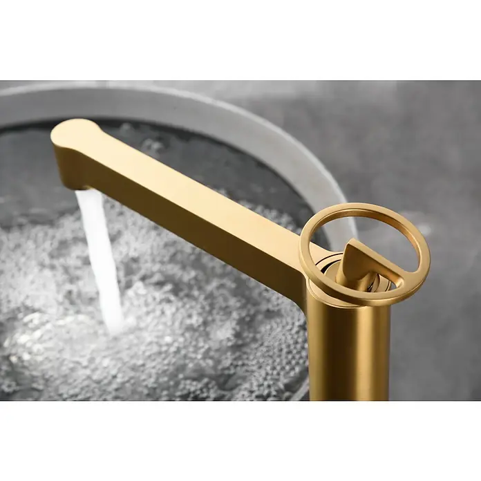 Imex Olimpo Grifo de lavabo alto - Oro - Un primer plano de un grifo dorado de baño con un mango en forma de anillo, que muestra agua fluyendo.