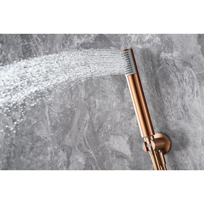 Imex Olimpo Sistema de ducha empotrado - Oro rosa - Primer plano de una moderna ducha de mano en oro rosa que rocía chorros de agua contra un fondo de mármol gris. Diseño elegante para tu baño.