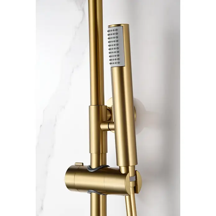 Imex Olimpo Sistema de ducha - Grifo monomando, Oro - Primer plano de un sistema de ducha dorado con un cabezal de ducha de mano contra una pared de mármol. El diseño es moderno y elegante.