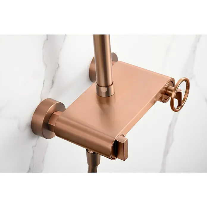 Imex Olimpo Sistema de ducha - Grifo monomando, Oro rosa - Primer plano de un elegante accesorio de ducha en oro rosa con estante y rueda de control, montado en una pared de mármol.