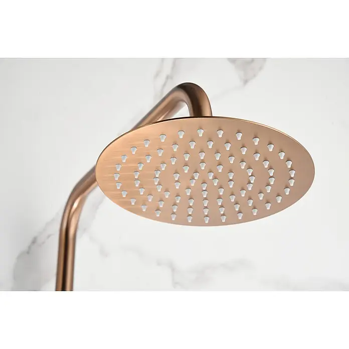 Imex Olimpo Sistema de ducha - Grifo monomando, Oro rosa - Primer plano de un moderno cabezal de ducha redondo con acabado de cobre y boquillas blancas sobre un fondo de mármol blanco.