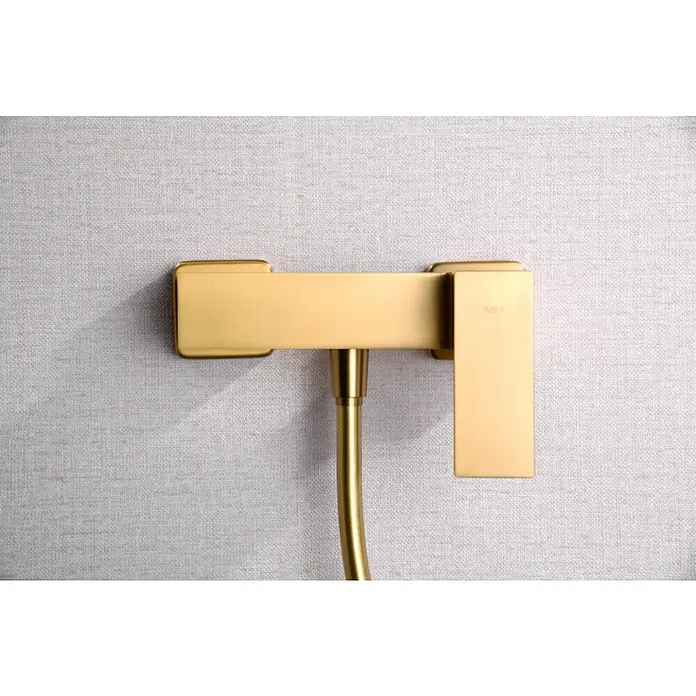 Imex Pisa Grifo de ducha - Oro - Primer plano de un mezclador de ducha dorado IMEX contra una pared texturizada, que muestra un diseño de baño elegante y moderno.
