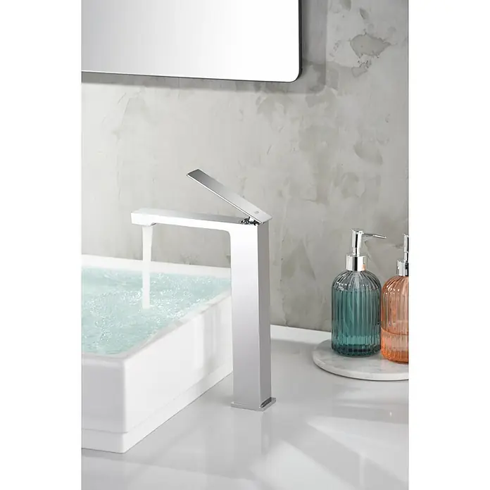 Imex Pisa Grifo de lavabo alto - Cromo - Aquí hay un primer plano de un grifo plateado moderno con agua clara que fluye hacia un elegante lavabo blanco.