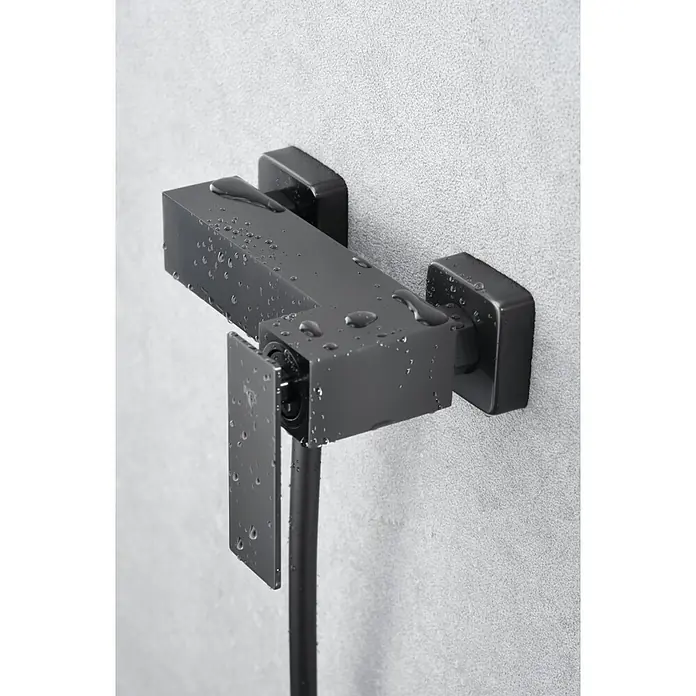 Imex Pisa Grifo de ducha - Black gun - Grifo de ducha moderno y cuadrado en negro con gotas de agua en la superficie, montado en una pared gris.