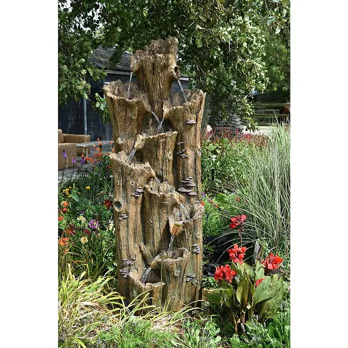 Ubbink AcquaArte Standbrunnen Tiros - 70 x 74 x 200 cm - Die mehrstufige Baumstumpf-Gartenbrunnen-Skulptur ist von üppiger Vegetation umgeben und schafft eine ruhige und natürliche Atmosphäre.