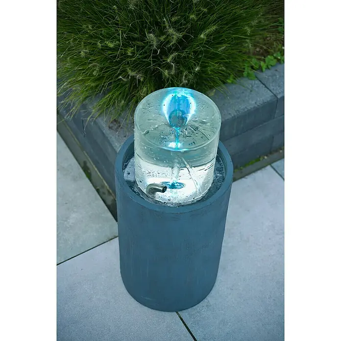 Ubbink AcquaArte Standbrunnen Salemi - 30 x 30 x 67 cm - Nahaufnahme eines dekorativen Wasserbrunnens mit einer blauen LED-Leuchte in einem zylindrischen Behälter im Freien.
