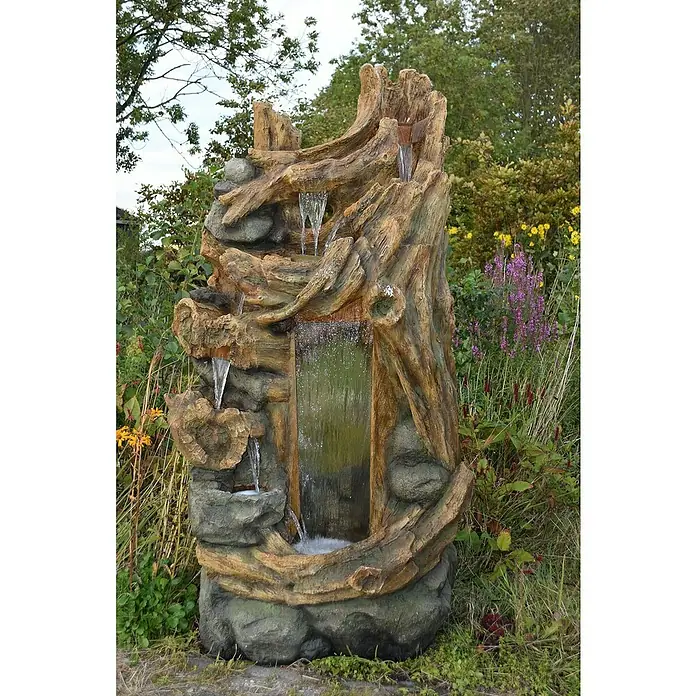Ubbink AcquaArte Standbrunnen Sartene - 79 x 100 x 180 cm - Ein dekorativer, mehrstufiger Gartenbrunnen in Holz- und Steinoptik, umgeben von üppigem Grün, der eine friedliche Atmosphäre schafft.