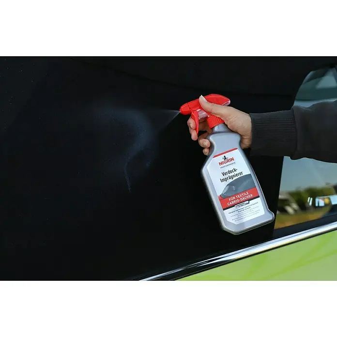 Nigrin Performance Verdeck-Imprägnierer - 500 ml, Geeignet für: Textile Cabrioverdecke - Nigrin Textil-Imprägnierer für Cabriodächer in Aktion: Eine Hand sprüht das Produkt auf ein schwarzes Stoffverdeck.