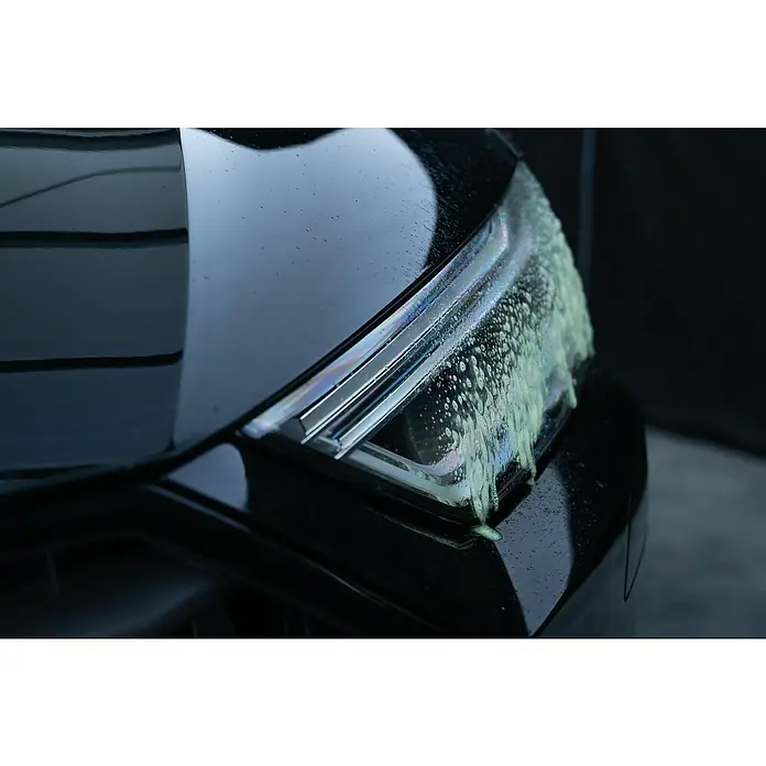 Nigrin Insektenentferner Power - 750 ml - Nahaufnahme eines Autoscheinwerfers, der mit Reinigungsschaum bedeckt ist, was die Autopflege hervorhebt.