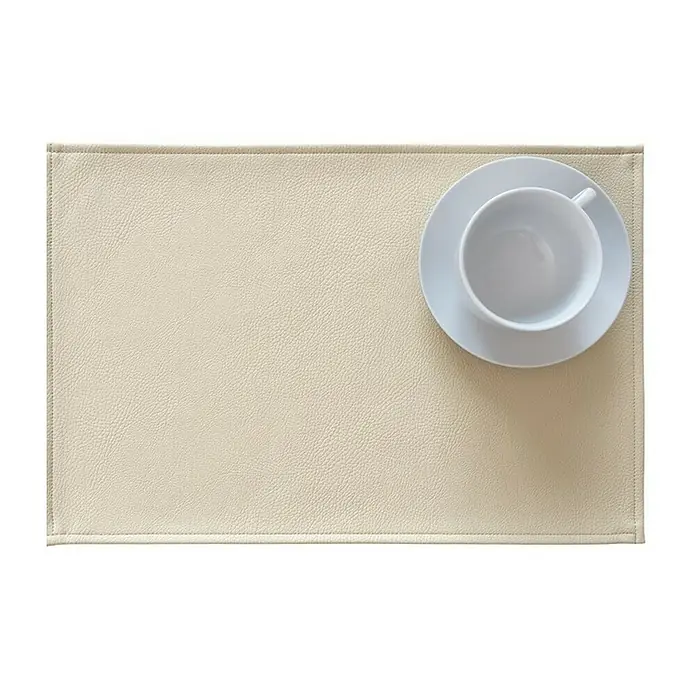 Tisch-Set Monaco - Sand, 45 x 30 cm - Beiger Platzdeckchen aus Leder mit einer weißen Tasse und Untertasse darauf. Elegantes Tischaccessoire für den täglichen Gebrauch.