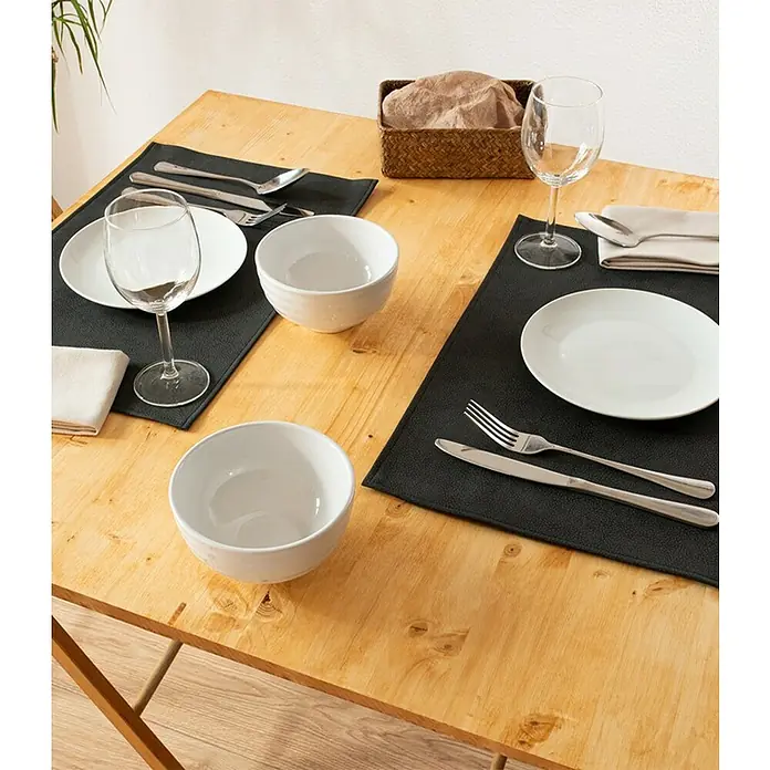 Tisch-Set Monaco - Black, 45 x 30 cm - Ein gedeckter Tisch mit Tellern, Schüsseln, Besteck und Gläsern auf schwarzen Platzsets, ideal für ein stilvolles Abendessen.