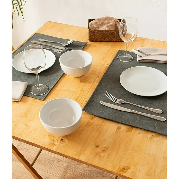 Tisch-Set Monaco Raw - Storm Grey, 45 x 30 cm - Ein gedeckter Tisch mit grauen Platzsets, weißen Tellern und Schüsseln, Weingläsern und Besteck, arrangiert für ein elegantes Esserlebnis.