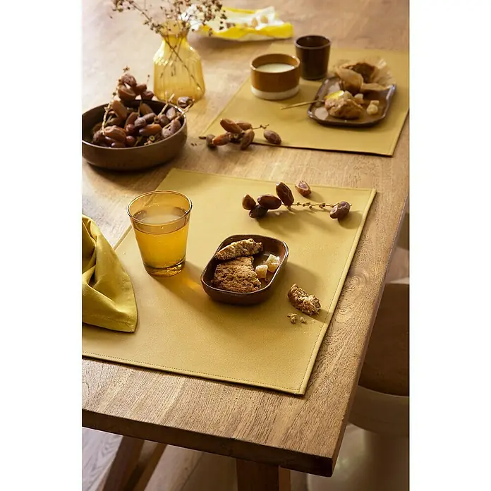 Tisch-Set Monaco Raw - Ocre, 45 x 30 cm - Gelbe Tischsets auf einem Holztisch mit Datteln, Gebäck und Getränken für eine gemütliche Mahlzeit.