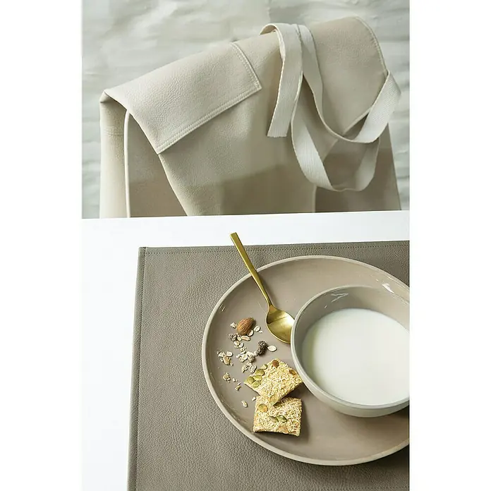 Tisch-Set Monaco - Taupe, 45 x 30 cm - Nahaufnahme von einem Frühstücks-Set mit einer grauen Tischdecke, einem Teller mit Müsli, Keksen, einer Schüssel Milch und einem goldenen Löffel.