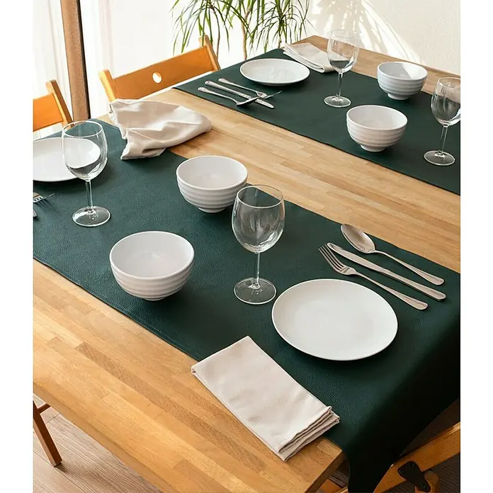 Tischläufer Monaco - 140 x 45 cm, Jungle Green - Ein Esstisch ist mit zwei grünen Tischläufern, Geschirr, Gläsern und Servietten für ein elegantes Abendessen gedeckt.
