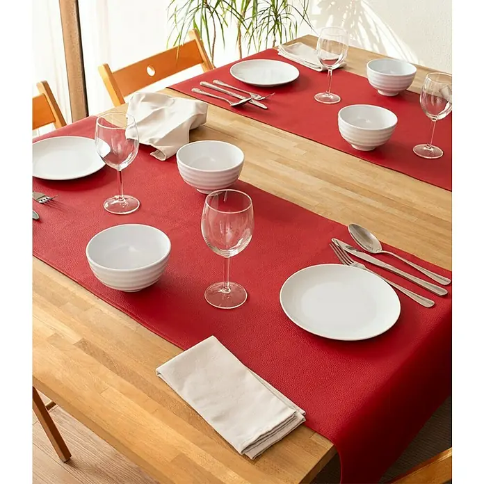 Tischläufer Monaco - 140 x 45 cm, Red - Einladende Tischszene mit roten Tischläufern, weißen Tellern, Schüsseln und eleganten Weingläsern auf einem warmen Holztisch. Perfekt für stilvolle Abendessen.