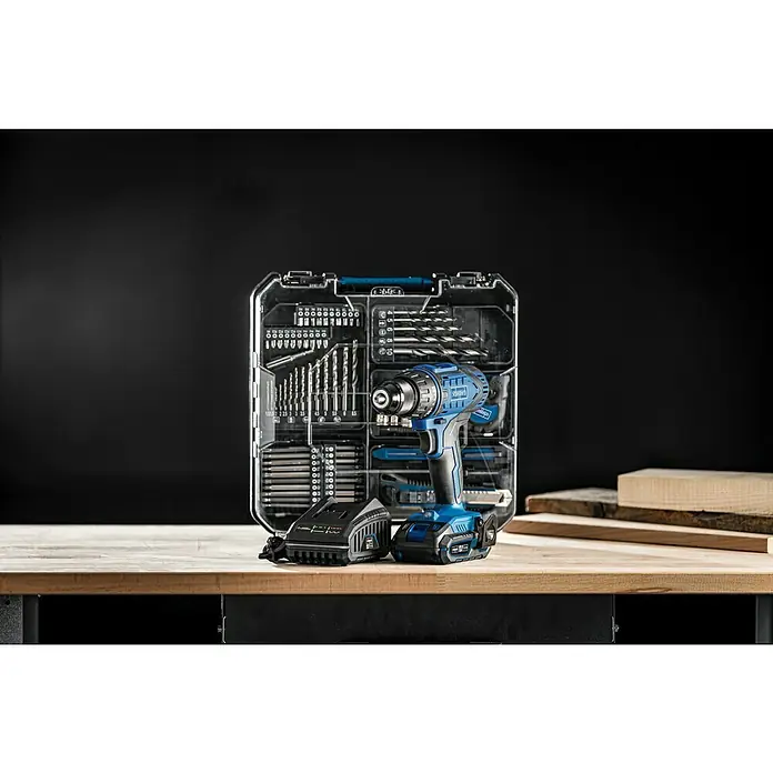 Scheppach IXES 20V Taladro atornillador de batería C-CDTB74/2-X - 20 V, 2 baterías, 2 Ah, 50 Nm, 77 pzs. - Taladro inalámbrico con estuche de accesorios transparente y batería, presentado sobre un banco de trabajo sobre fondo oscuro.