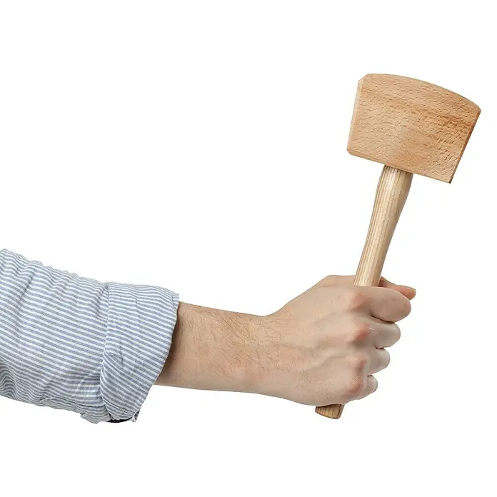 Heka Schreinerklüpfel - Maße Kopf: 100 x 60 mm, 4-Kant - Holzhammer in der Hand. Der Holzhammer mit hellem Holzgriff wird von einer Hand in einem blau-weiß gestreiften Hemd gehalten.