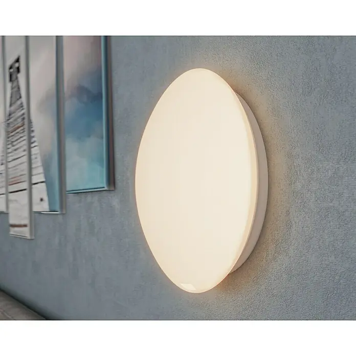 Steinel Sensor-Wand- & Deckenleuchte RS 16 L weiß - 60 W, L x B x H: 27,5 x 27,5 x 9,5 cm, Weiß, E27 - Nahaufnahme einer runden, weißen Wandleuchte, die an einer strukturierten Wand befestigt ist und ein sanftes, warmes Licht ausstrahlt.