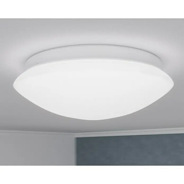 Steinel Sensor-Wand- & Deckenleuchte RS 16 L weiß - 60 W, L x B x H: 27,5 x 27,5 x 9,5 cm, Weiß, E27 - Nahaufnahme einer runden, weißen Deckenleuchte, die an einer weißen Decke montiert ist und ein sanftes, diffuses Licht ausstrahlt.