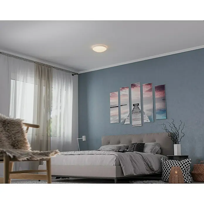Steinel Sensor-Wand- & Deckenleuchte RS 16 L weiß - 60 W, L x B x H: 27,5 x 27,5 x 9,5 cm, Weiß, E27 - Helle Deckenleuchte in einem Schlafzimmer mit einem Bett, einem Stuhl und einer Wand mit Kunstwerken. Minimalistisches Design für stilvolle Beleuchtung.