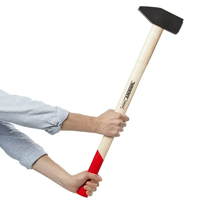 Wisent Vorschlaghammer5.000 g - Nahaufnahme eines Wissent-Hammers mit Holzstiel, der von einer Person mit Hemd gehalten wird. Das Werkzeug ist für Bau- und Abbrucharbeiten geeignet.