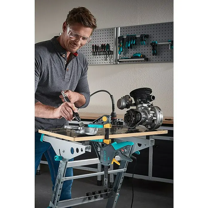 Wolfcraft Fächerschleifer - Körnung: 150, Arbeitsdurchmesser: 60 mm - Der Wolfcraft Werktisch im Einsatz: Ein Mann bearbeitet ein Werkstück mit einem Werkzeug, unterstützt durch die vielseitige Spannvorrichtung.