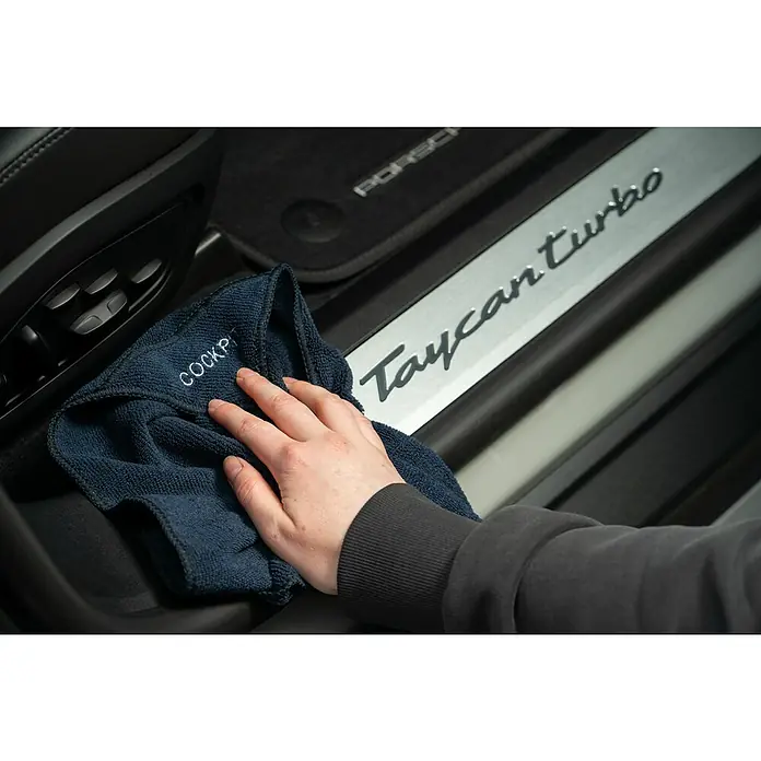 Nigrin Kunststoff-Reiniger SMART `N GREEN - 500 ml - Ein dunkelblaues Cockpit-Reinigungstuch wird in einem Porsche Taycan Turbo verwendet. Es sorgt für Sauberkeit und Glanz im Fahrzeuginnenraum.
