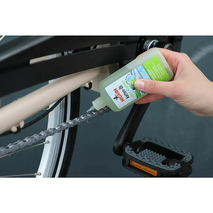 Nigrin Kettenöl SMART'N GREEN - 100 ml - Eine Person ölt eine Fahrradkette mit NIGRIN Ketten-Öl smart green, einem biologisch abbaubaren Schmierstoff für Fahrräder.