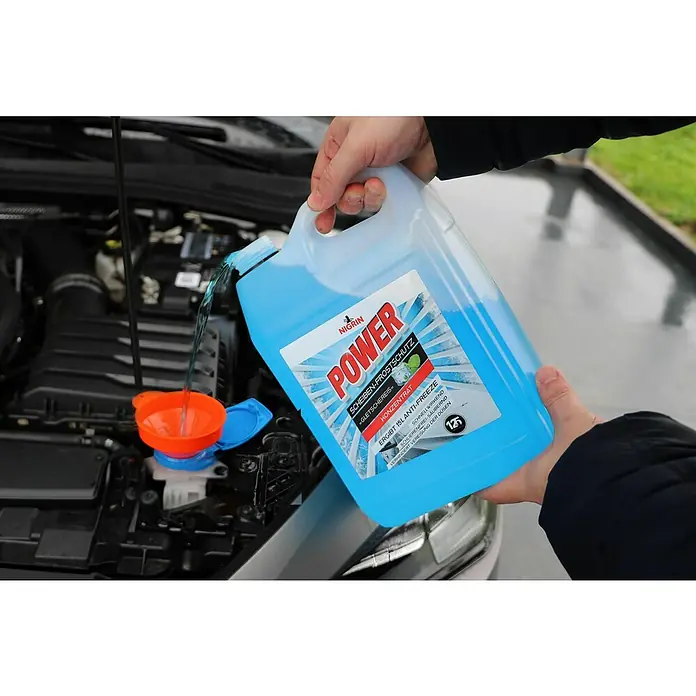 Nigrin Scheibenfrostschutz-Konzentrat - 5 l - Eine Person füllt Scheibenwaschflüssigkeit "Nigrin Power" in ein Auto. Das Produkt verspricht Frostschutz und schnelle Reinigung.