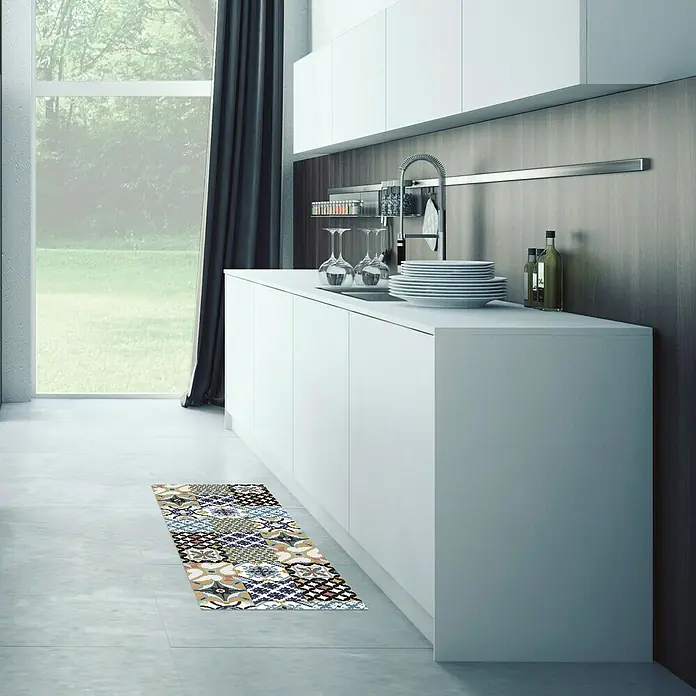 Alfombra de vinilo Croma hidráulico - Multicolor, 140 x 50 cm - Un corredor de cocina patchwork se encuentra en el piso de una cocina moderna con gabinetes blancos y una gran ventana.