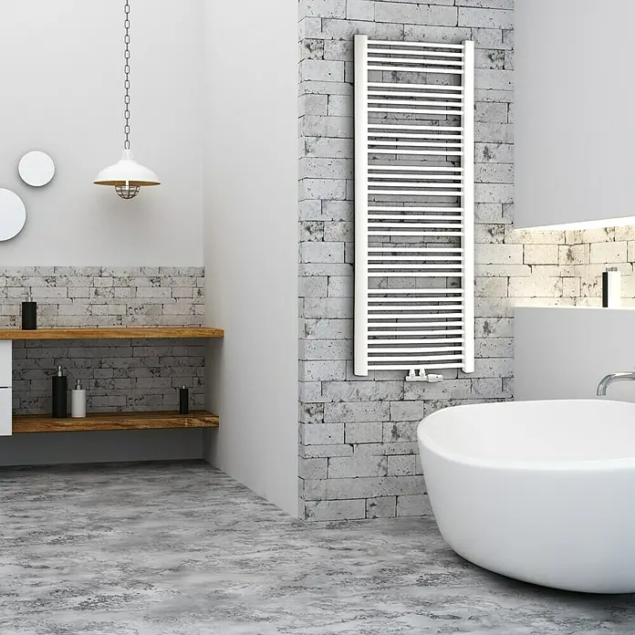 Camargue Badheizkörper Trapezo - B x H: 600 x 1.700 mm, Anschlusskombination Heizkörper: Mittig unten - Ein modernes Badezimmer mit einem weißen Badheizkörper an einer grauen Ziegelwand, ergänzt durch eine freistehende Badewanne.
